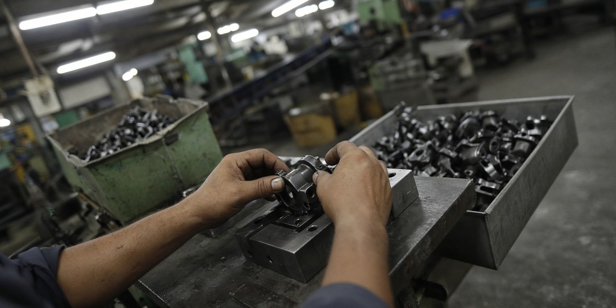 Egocentric view of a manufacturing plant worker inspecting metal parts at a workbench