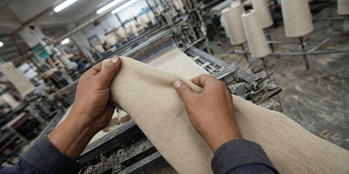 Egocentric view of a textile worker inspecting fabric on a loom in an Indian mill